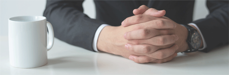 책상 위에 모은 두 손과 머그컵